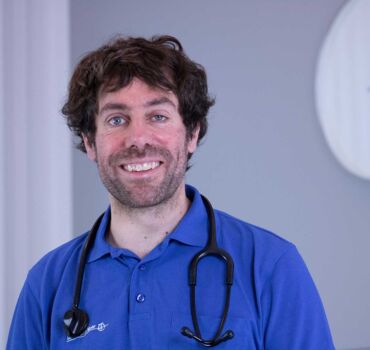 Ein Porträtfoto von Dr. med. Matthias Mohr - Internist | Kardiologe | Sportmediziner | Hypertensiologe | Lipidologe. Er trägt ein blaues Poloshirt und ein Stethoskop um den Hals.