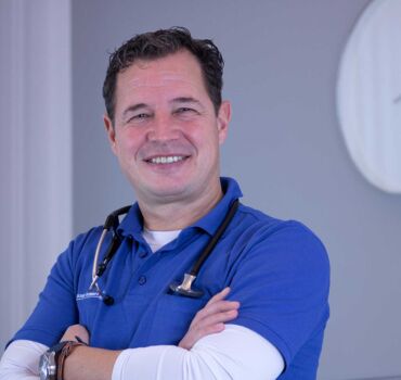 Ein Porträtfoto von Dr. med. Michael Schwarz - Internist | Kardiologe | Angiologe. Er trägt ein blaues Poloshirt und ein Stethoskop um den Hals.